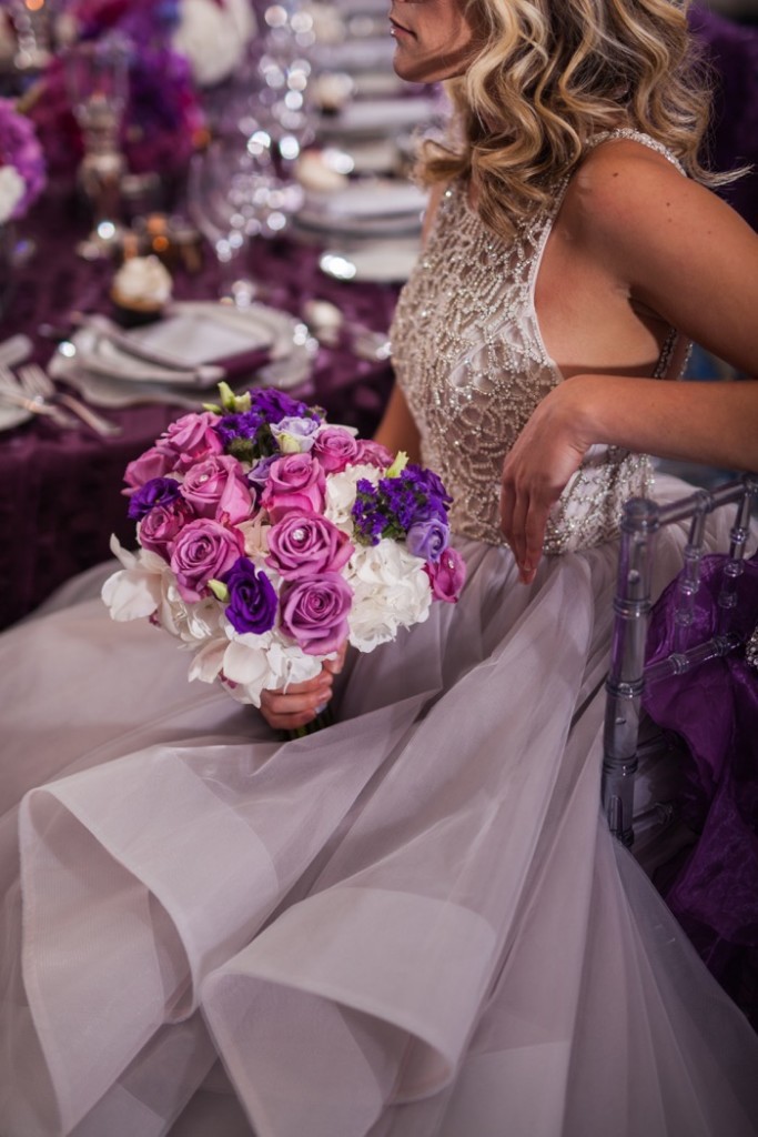Bride in shoulder less lace bodice and lavender skirt holding pink and purple rose bouquet 