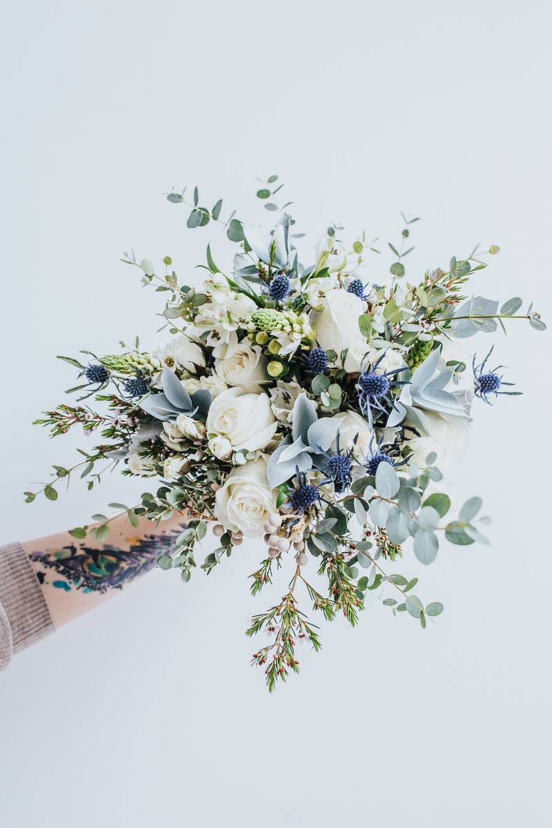 Baby blue and white bouquet with green and dark blue accents 