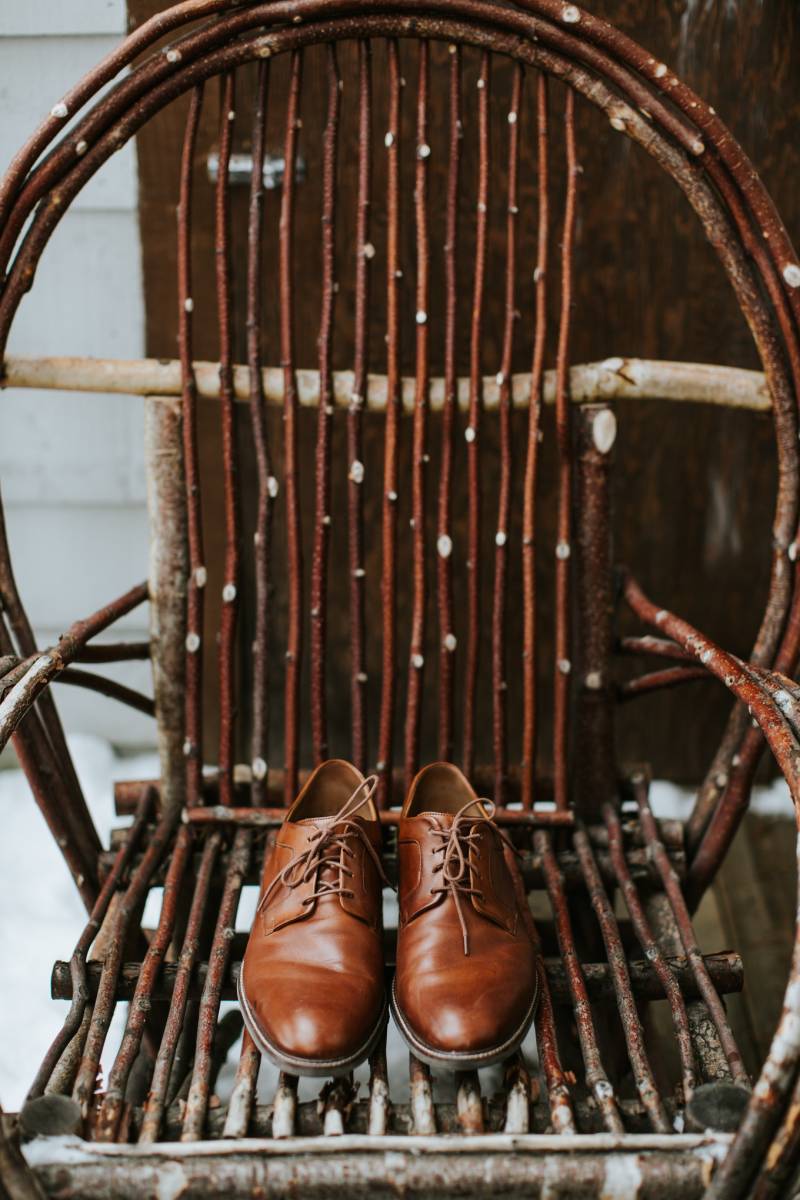 Brown dress shoes sitting on rustic wooden chair 