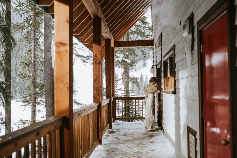 Woman entering cabin doorway on snowy wooden deck