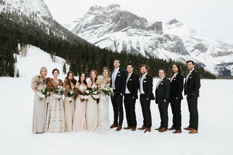 Brides and grooms standing in line at snowy mountain base 