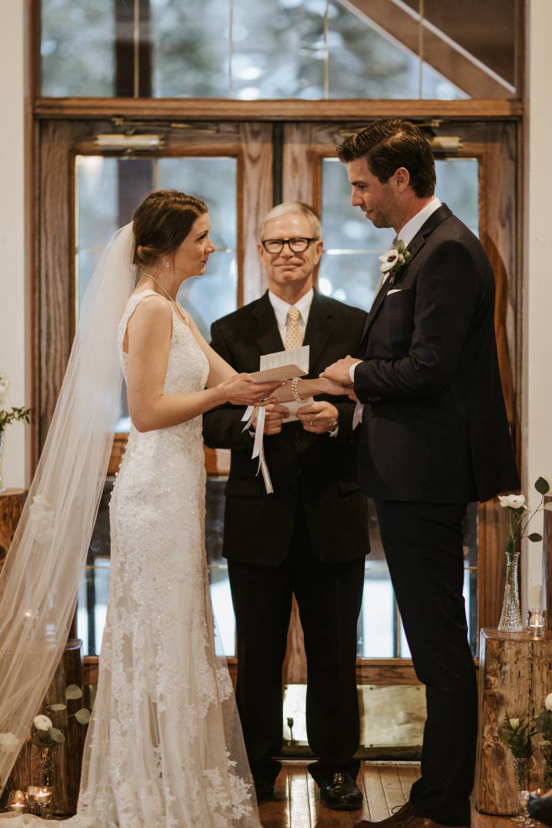 Bride and groom stand in front of officiant while saying vows 