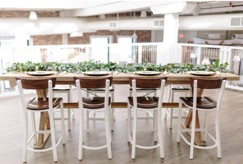 Dark wood seated chairs with white legs around long table with green table runner on top