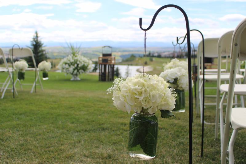 Wedding ceremony aisle with hanging white flowers in clear mason jars 