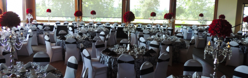 Wedding reception with white seating and large burgundy floral centerpiece on candelabra 