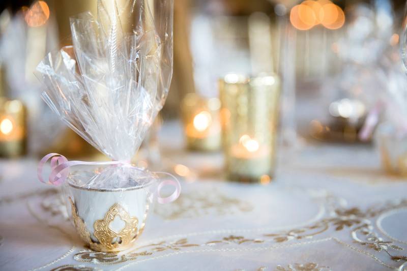 Small white and gold teacup in plastic bag with pink ribbon 