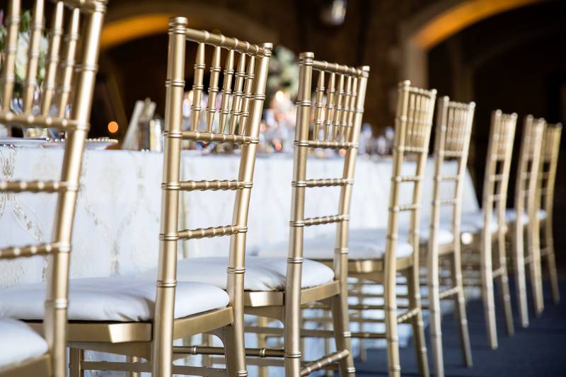 Gold framed chairs lined with white padding along edge of table 