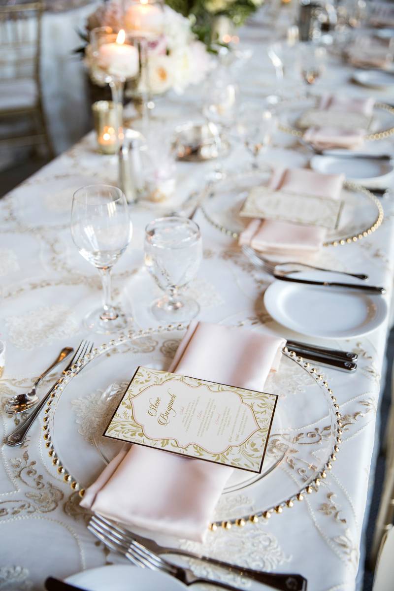Place setting with gold rimmed plate on white and gold tablecloth 