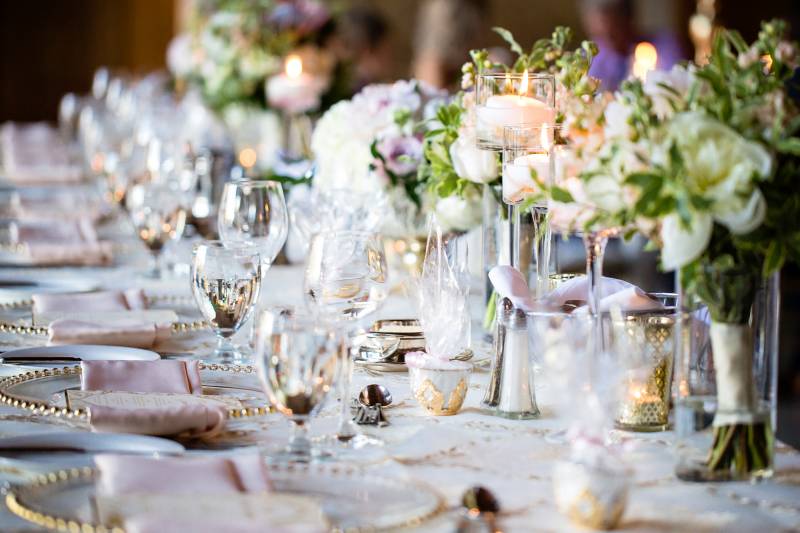 Table setting with gold place settings and white floral centerpieces 