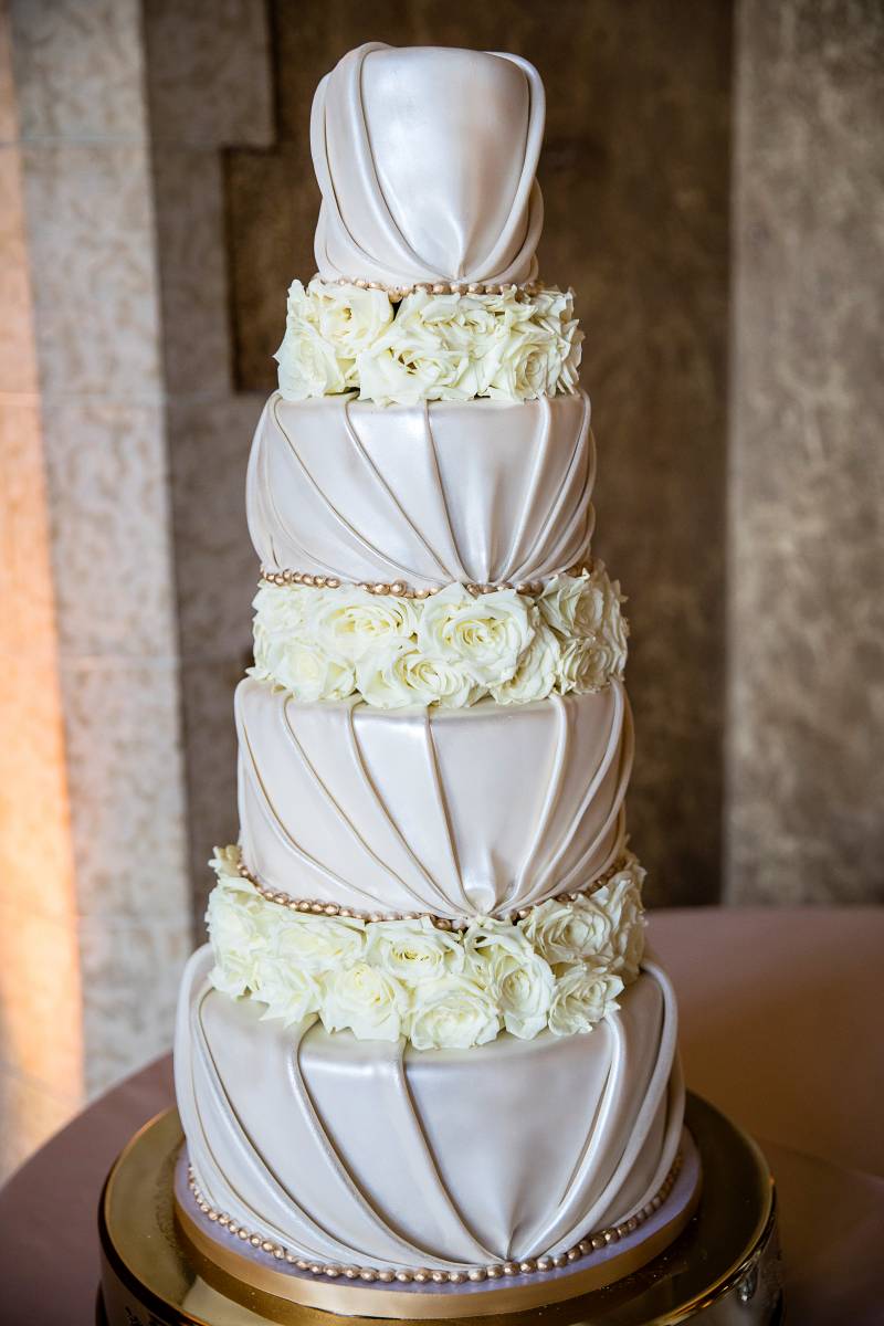 Large blush and white wedding cake with ripples and white flowers 