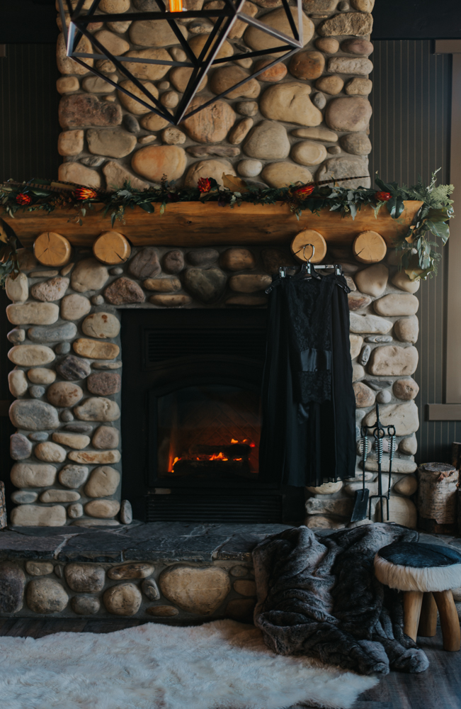 Large stone fireplace and wooden mantle with fur rug in front 