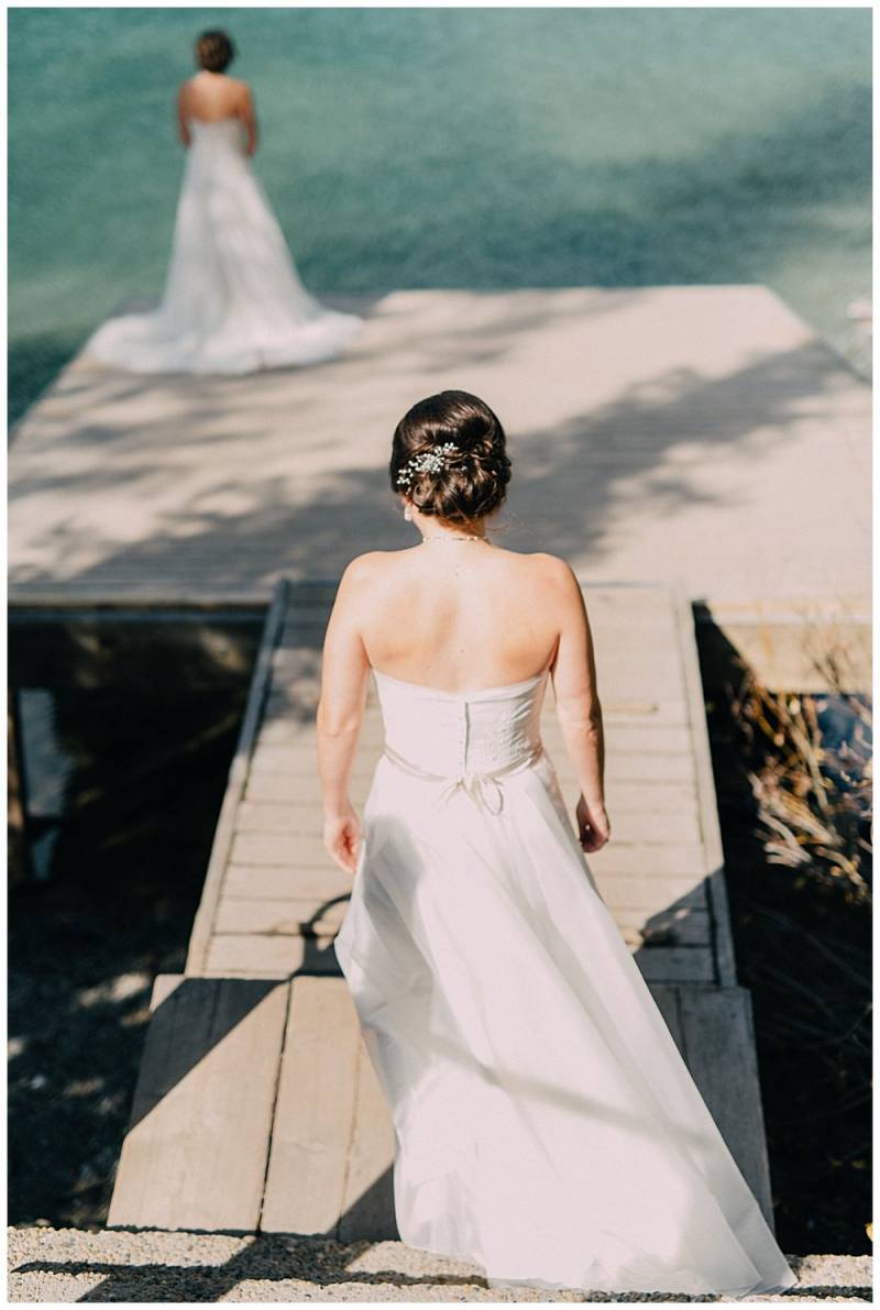 Bride walks towards bride on dock wearing white dress