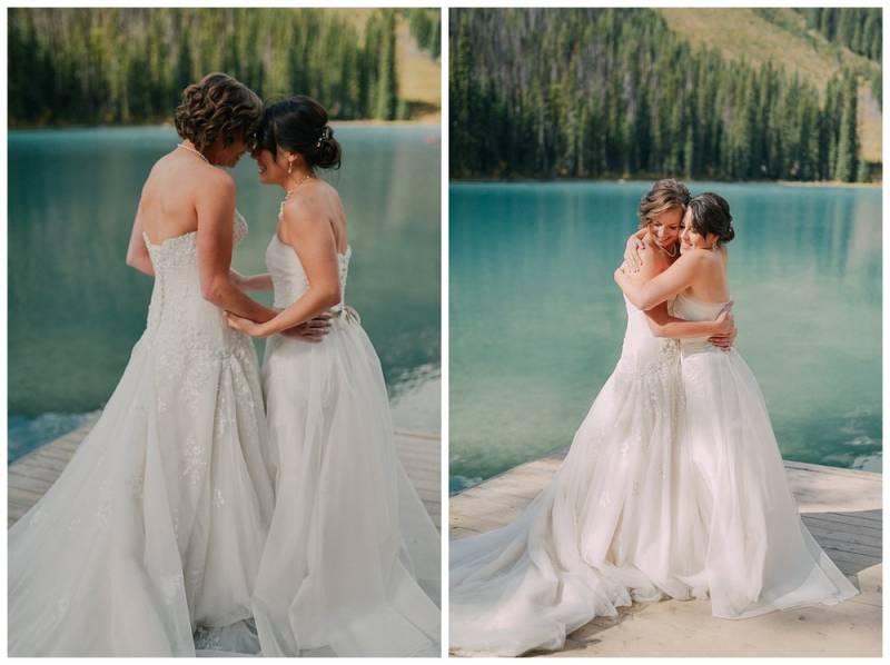 Bridesmaids embrace wearing white dresses at the edge of water