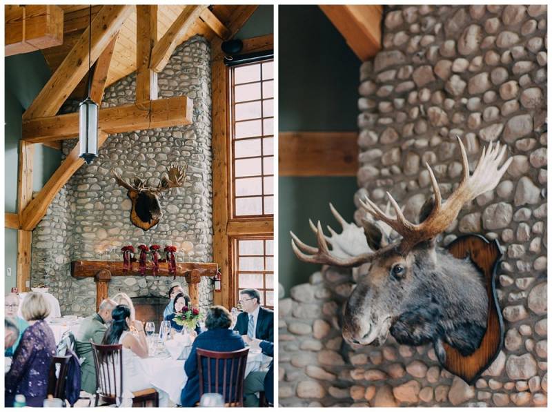 Cabin wedding reception with guests beside moose-head on stone mantle 