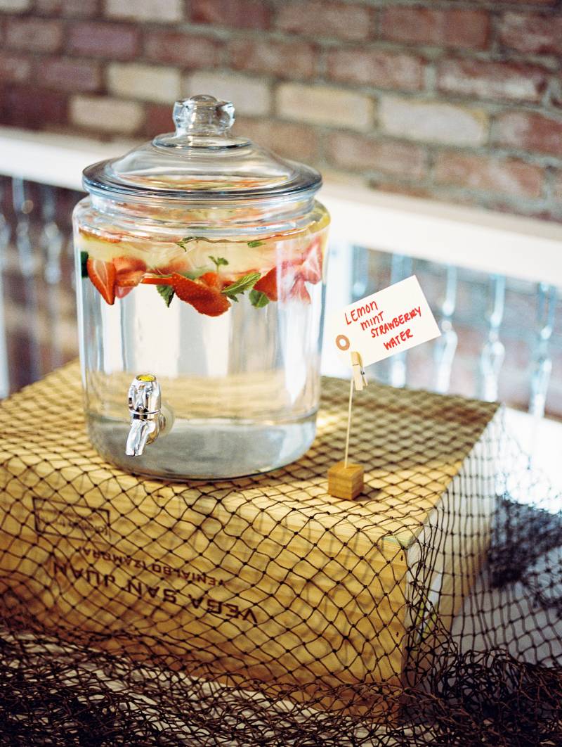 Glass jar with spout holding strawberry water on net on top of wood box