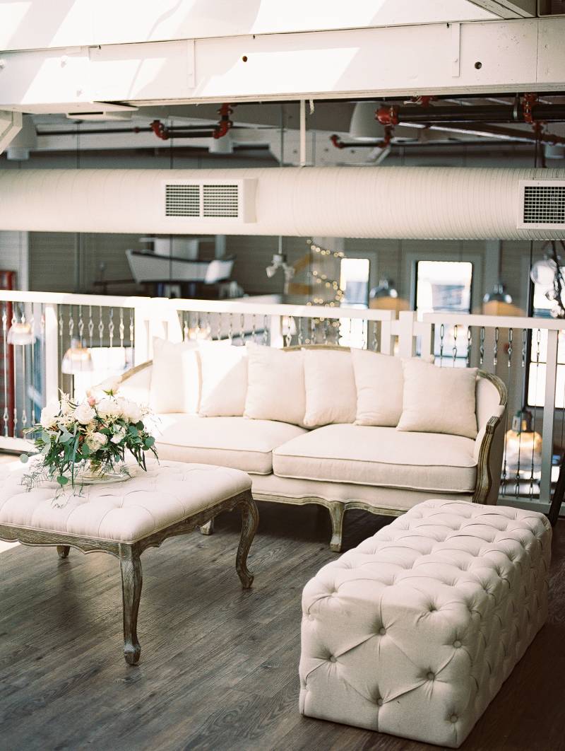 Cream loveseat and sofa and coffee table with white floral centerpiece in building loft 
