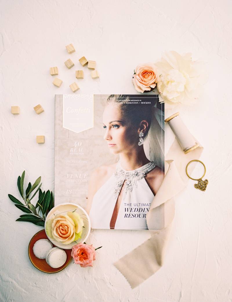 Wedding magazine flat lay with pale pink ribbon strewn and peach floral accents