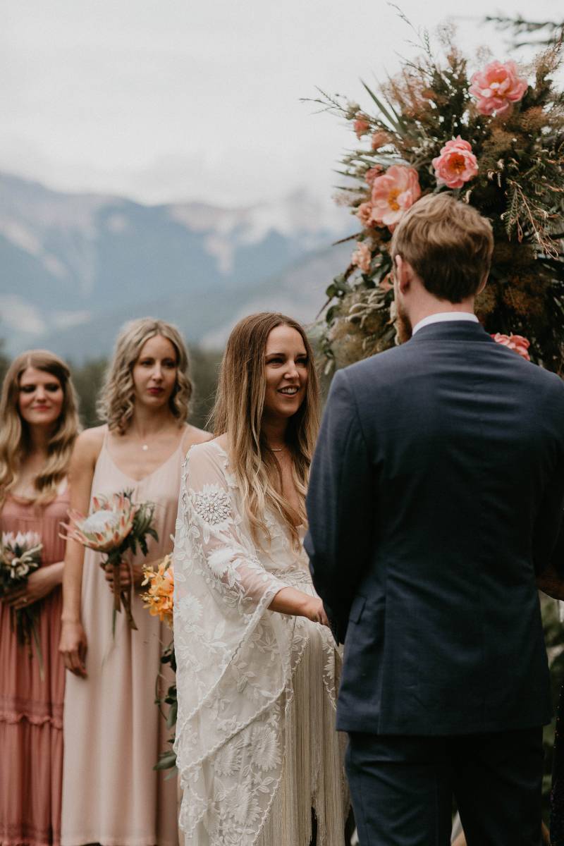 Wedding vows with bride and groom with blush floral arrangements in mountains 