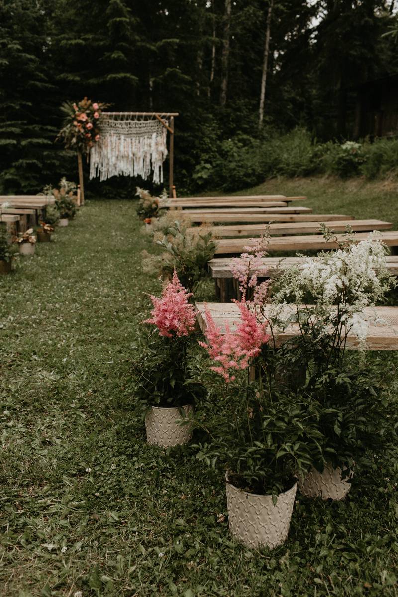 Outdoor Macramé wedding arch and wooden benches with blush floral accents