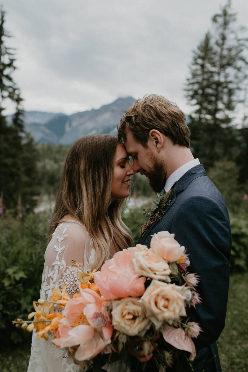 Bride and groom with blush bouquets and lace bodice dress in front of mountains 