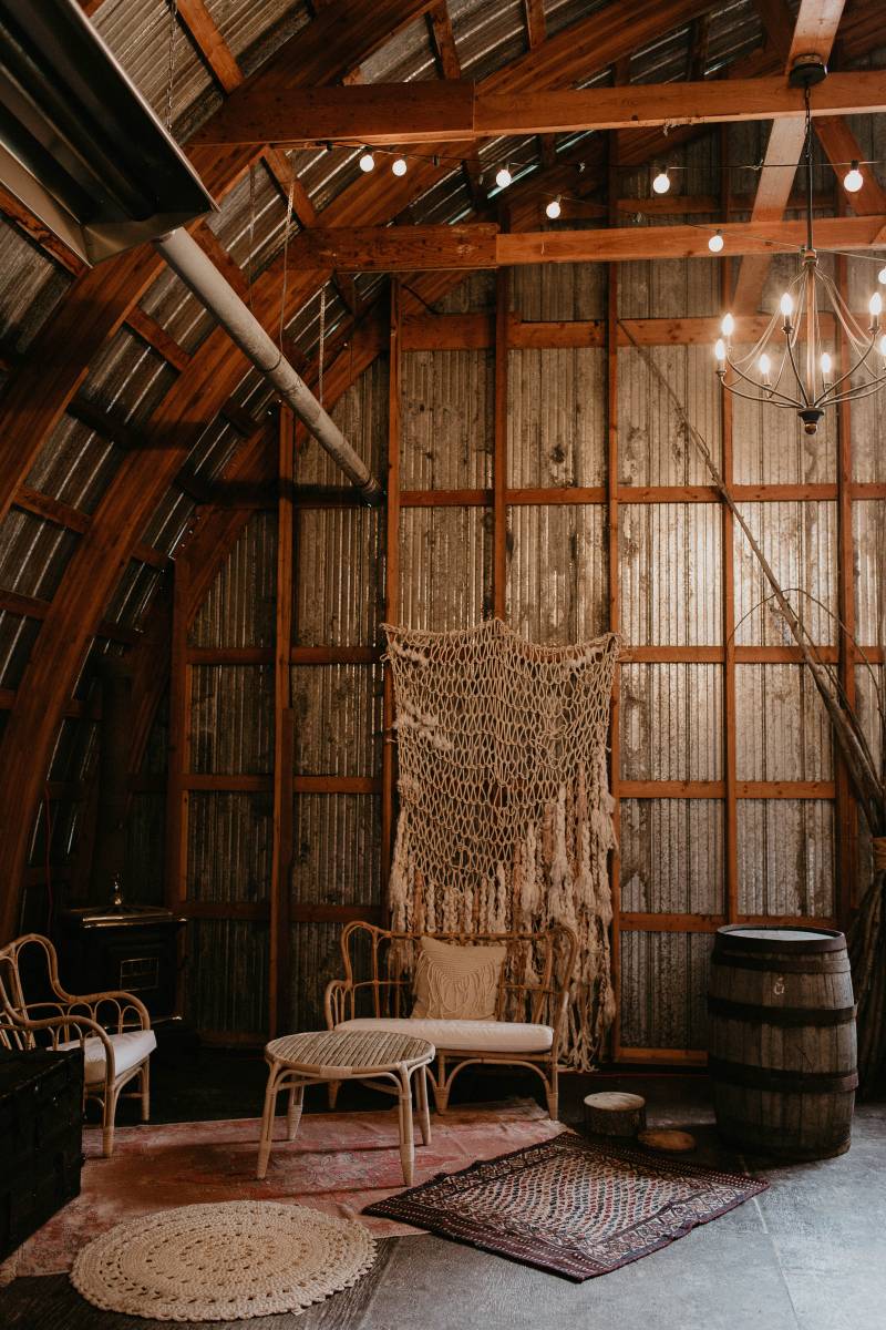 White macramé hanging on barn wall with wooden coffe table and chairs