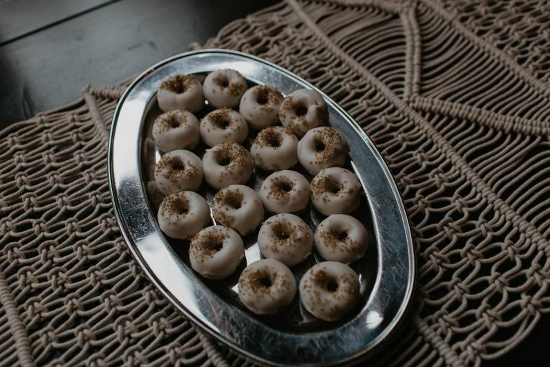 Miniature doughnuts with bronze sprinkles and glaze on macramé table lay