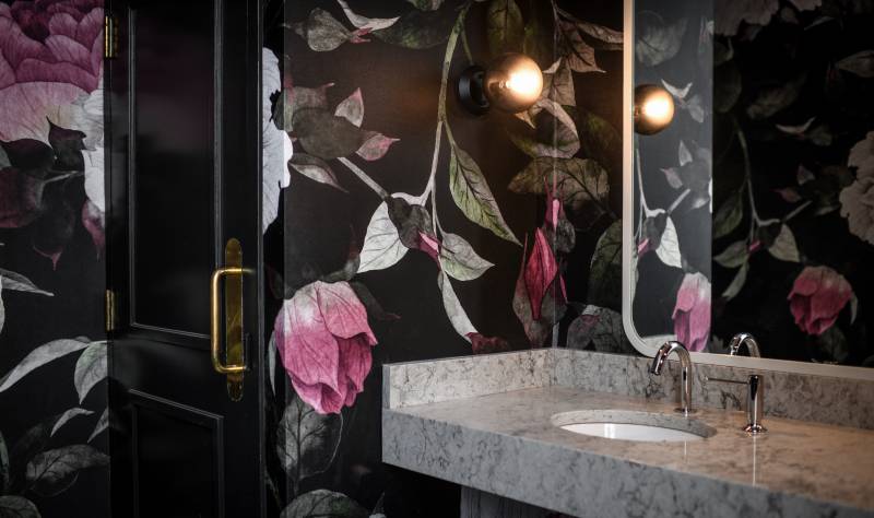 Marble countertop in bathroom with black and pink floral wallpaper 