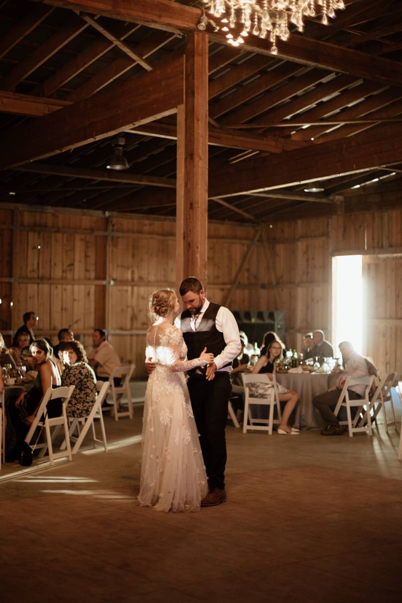 Bride and groom dance in wooden barn wedding reception 