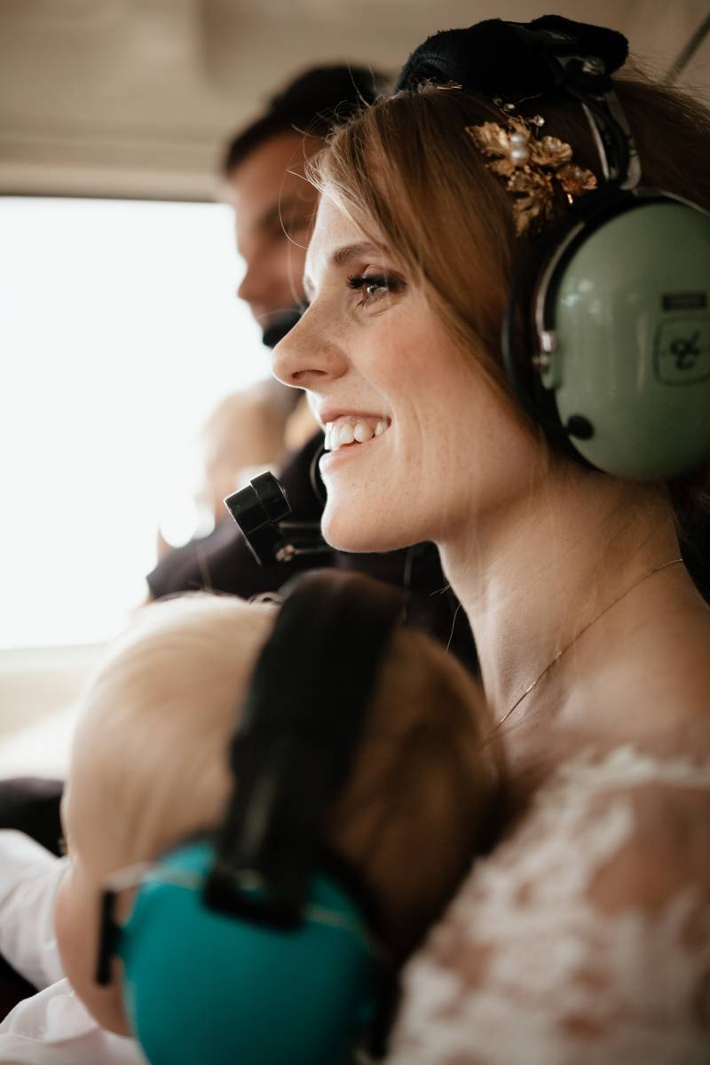 Bride and groom and child wearing earmuffs in helicopter 