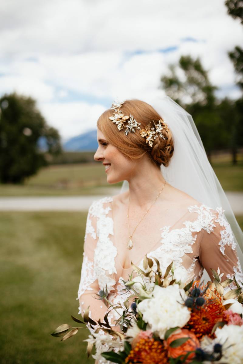 Bride with white lace bodice and white veil holding blush and orange bouquet 