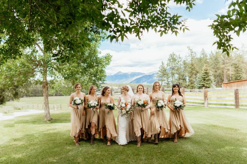 Bride and bridesmaids wearing blush dresses holding white bouquets 