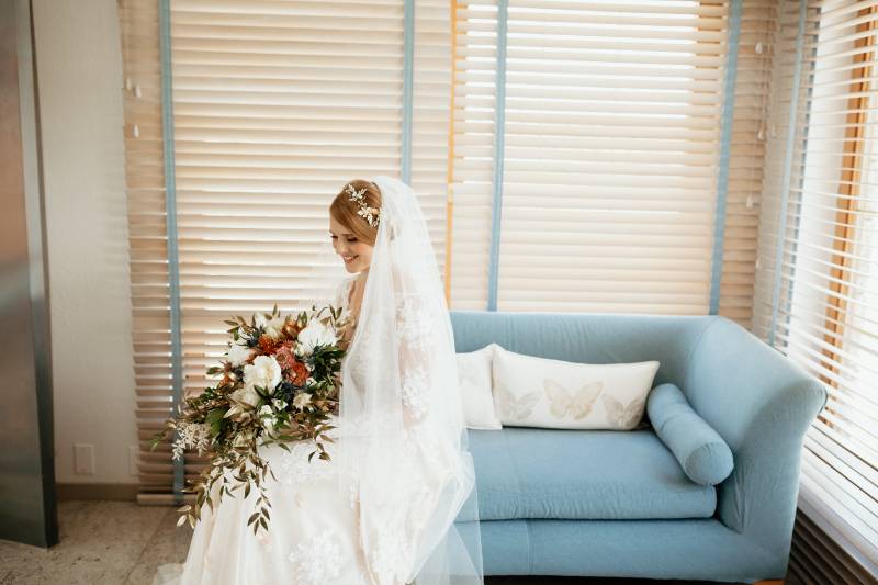 Bride wearing white veil and flower crown holding bouquet with white and blush flowers 