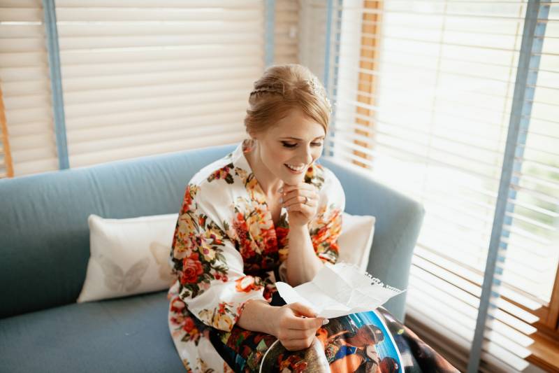 Bride in floral kimono looking at paper on blue sofa