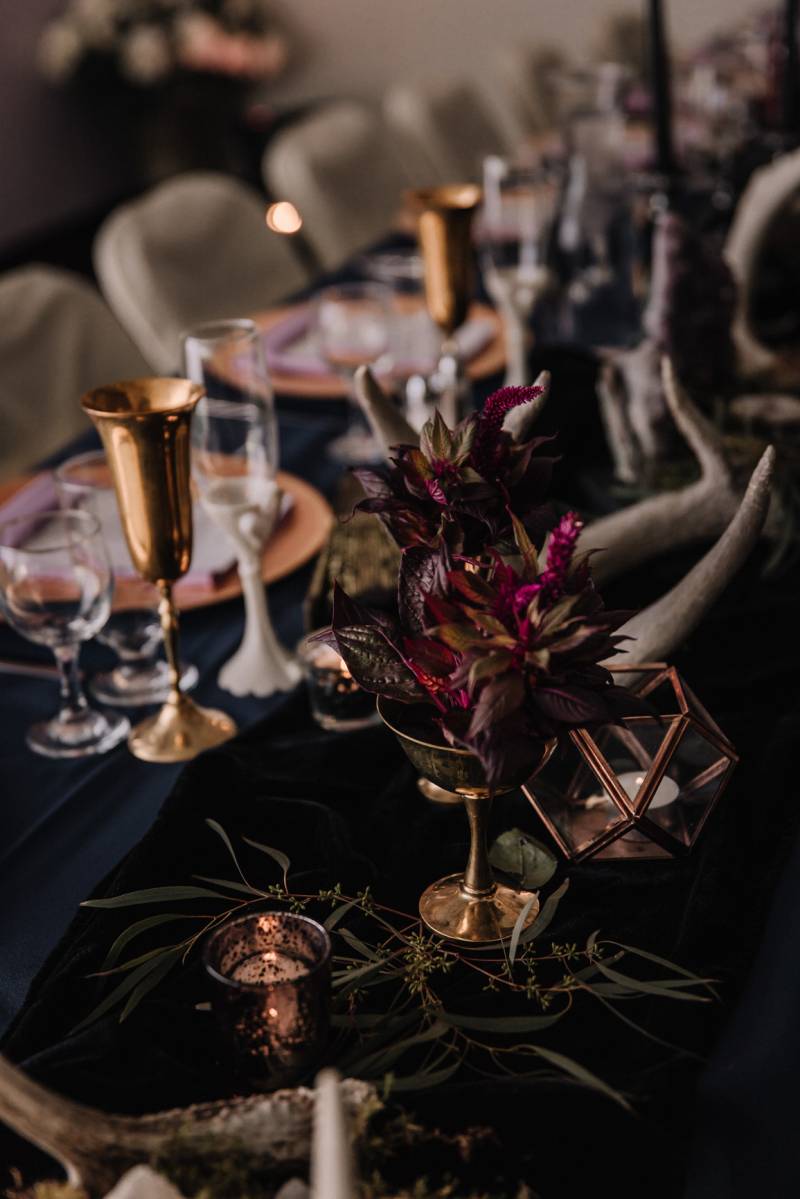 Bronze and gold centerpiece on black table with burgundy floral arrangements 