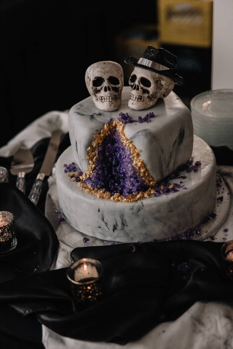 White marble wedding cake with purple and gold cut and his and hers skull decoration 