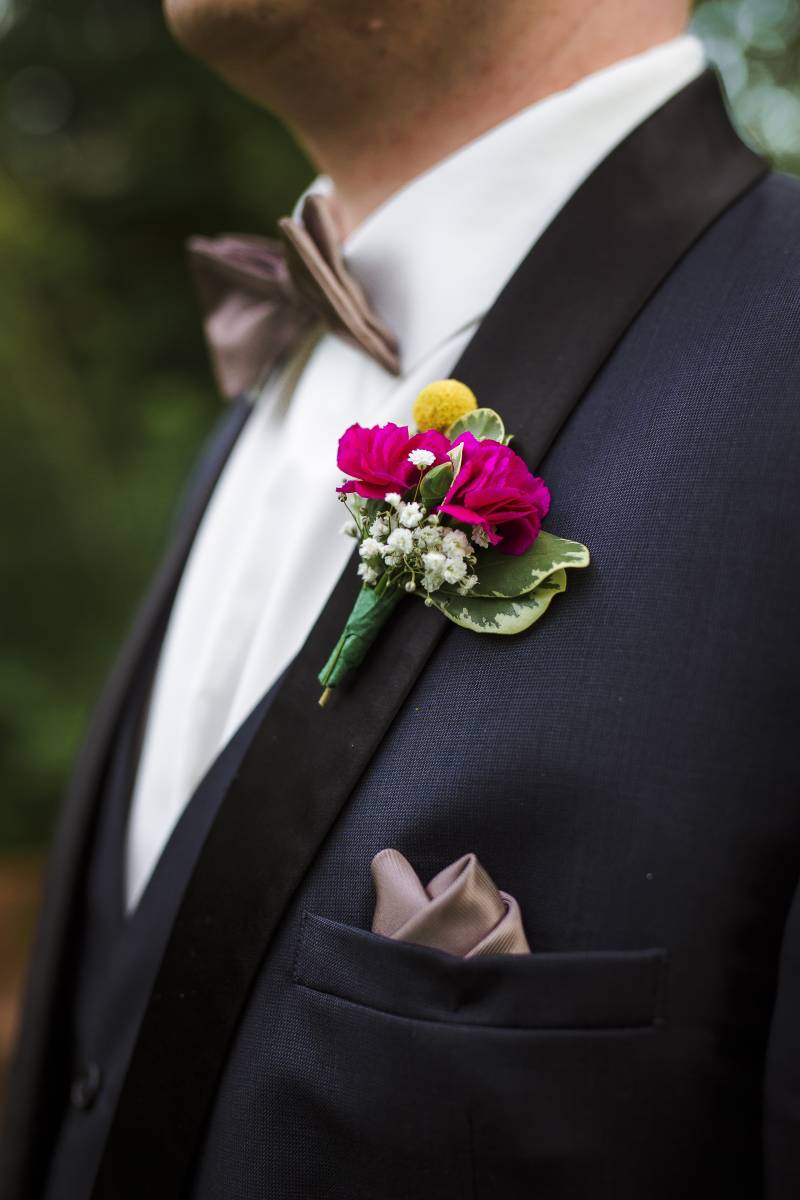Purple and yellow boutonniere on black suit