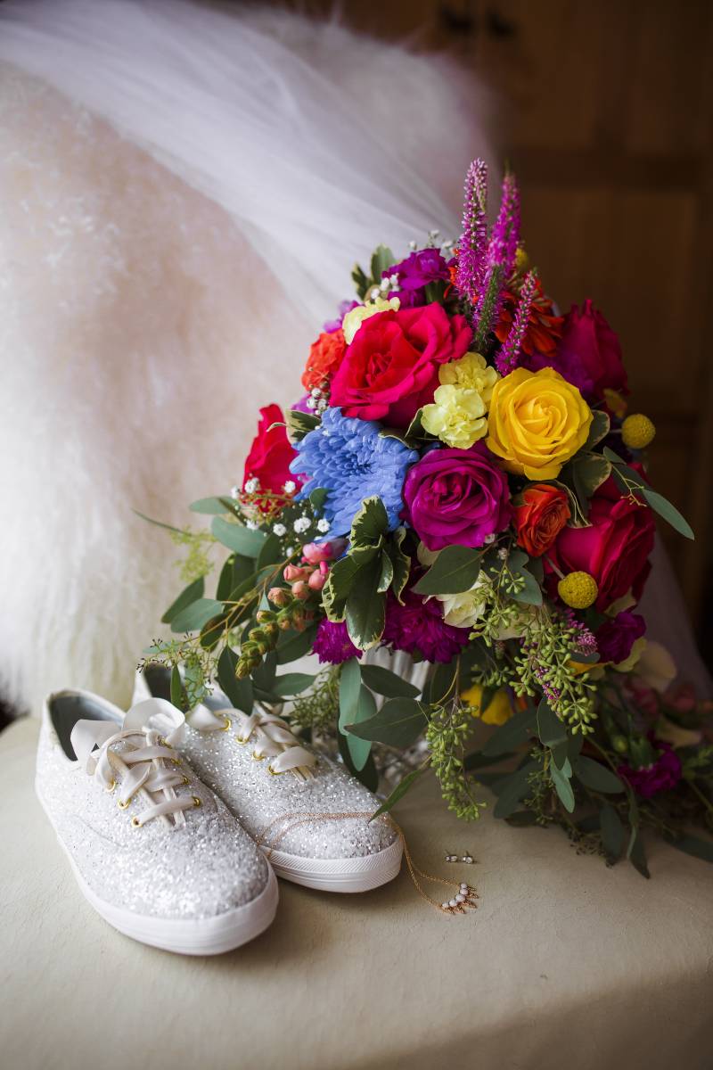 Lush red yellow and purple bouquet beside sparkling sneakers 