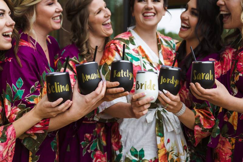 Bridesmaids and bride holding mugs with gold lettering names 