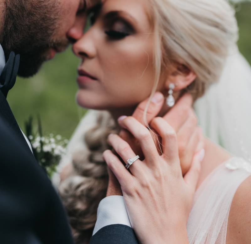 Groom touches brides neck touching foreheads wedding ring 