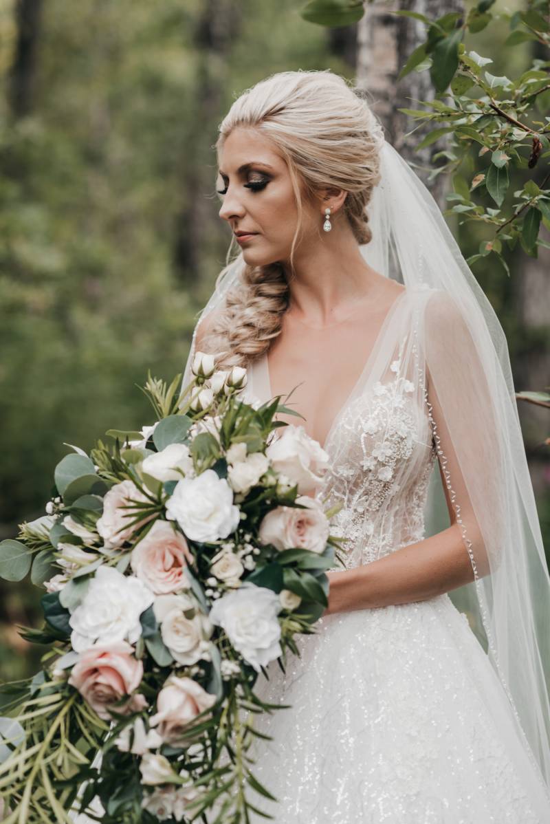 Bride holds blush and white bouquet looking off to side 
