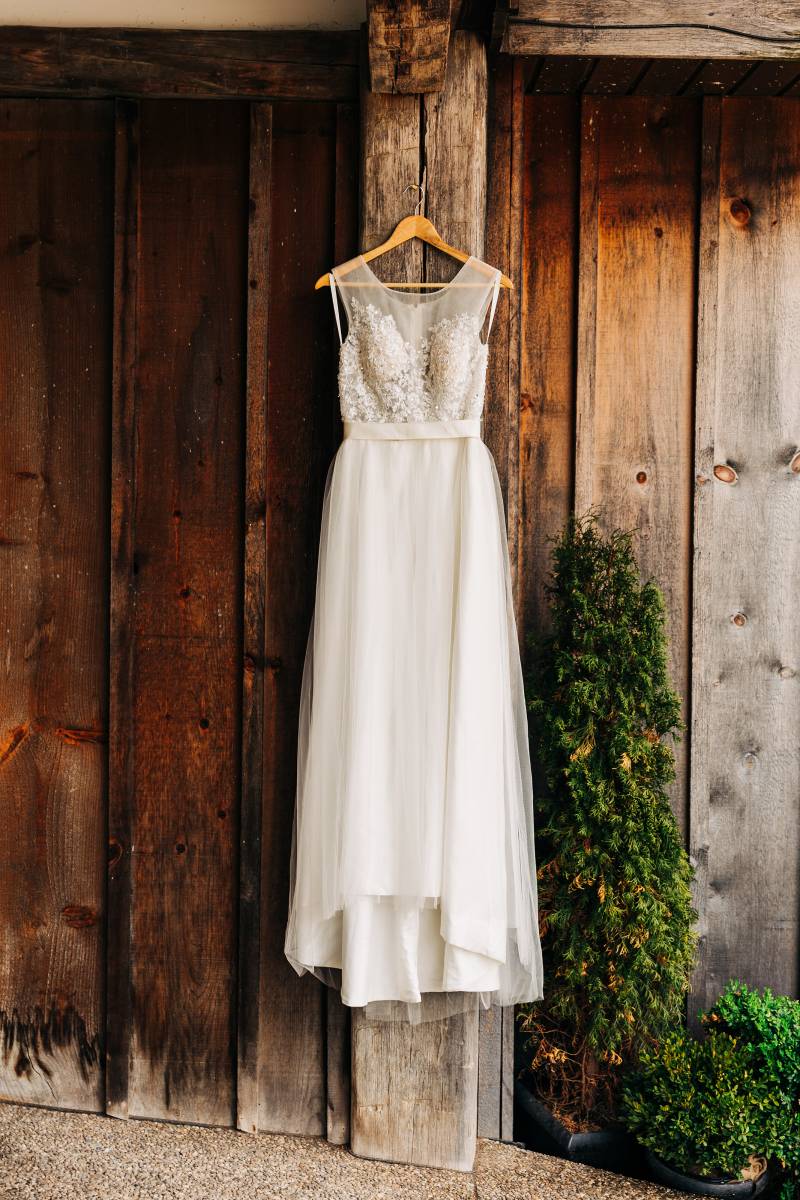 Wedding dress with lace bodice hanging off a barn wall 