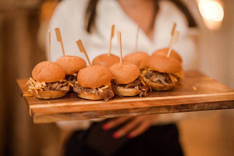Several sliders with wooden spits on wood platter 