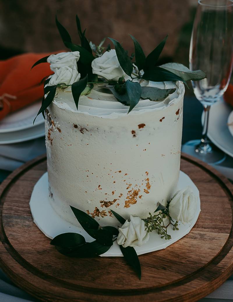 White naked wedding cake with white and green floral accents 