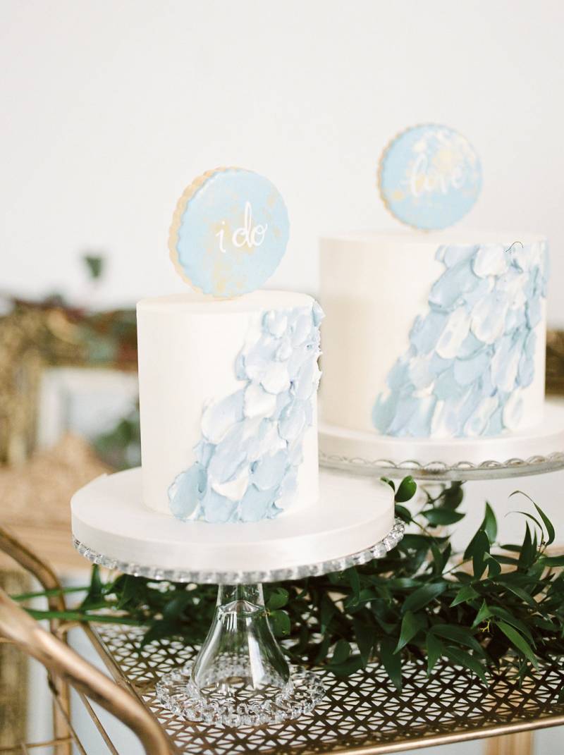 Individuals white wedding cakes with powder blue accents on golden trolley with leaves