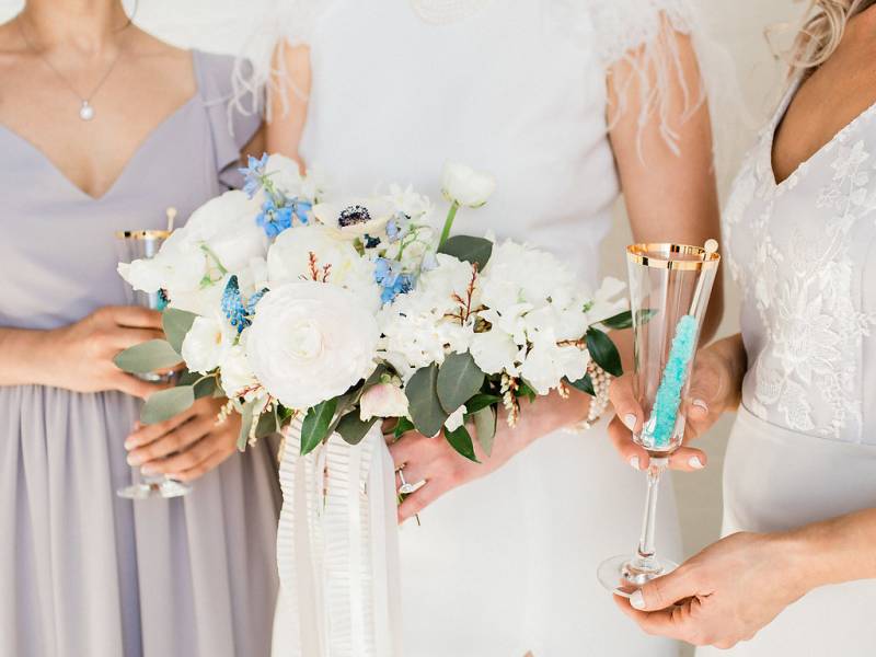Three woman in white and beige dresses holding bouquet and gold rimmed glasses 