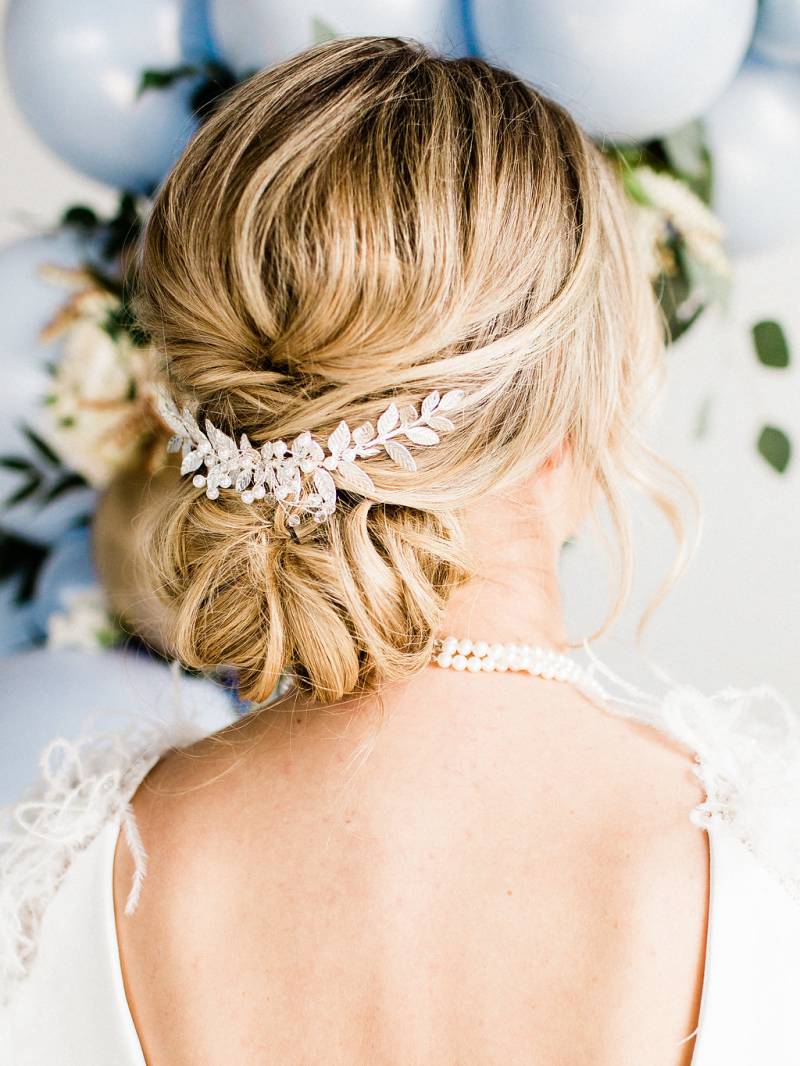 Blond hair and bun of woman wearing pearl necklace and white open back dress