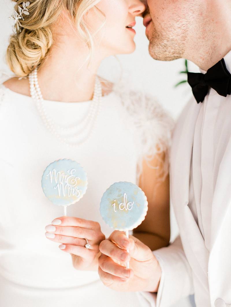 Man and woman nearly kiss while holding light blue cake pops 