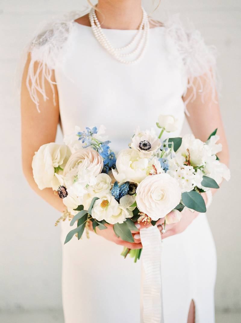 Cream white and blue bouquet held by woman in white dress
