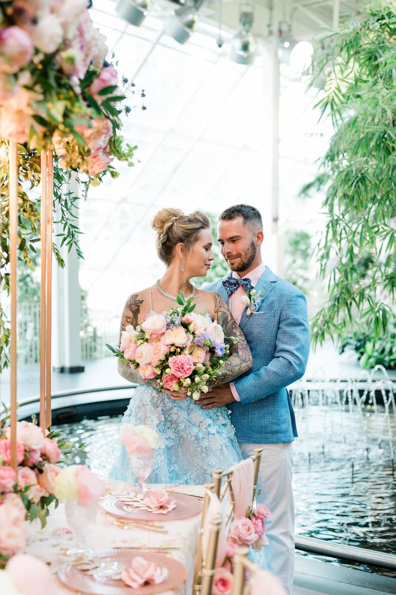 Man embracing woman holding lush pink bouquet behind 