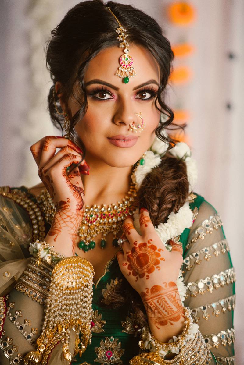 Woman in green dress sits with henna tattoos on wrist and arms